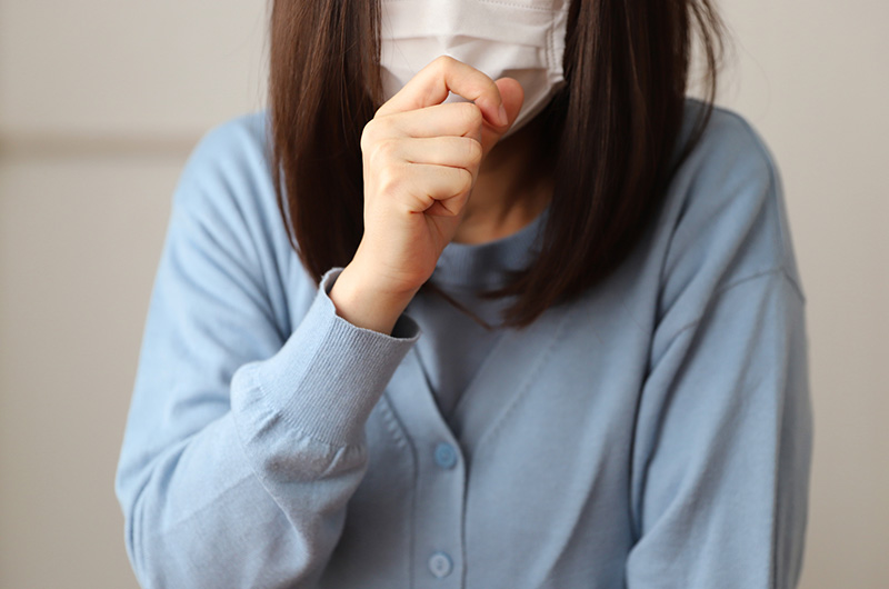 マスクをし咳をする女性